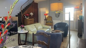 A living room with a staircase, a sofa, a chair, and a lamp.