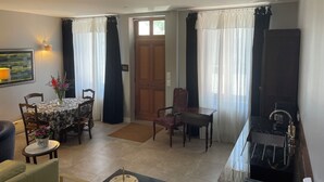 A living room with a dining area, a fireplace, and a door leading to another room.