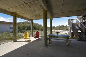 An outdoor covered area with a picnic table and two Adirondack chairs, a staircase, and a building in the background. - Big Views! Direct Beach Boardwalk Access! (St George Island)