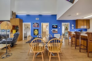 A modern living room with a blue accent wall, wooden furniture, and various artworks.