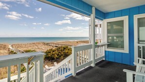Een balkon met uitzicht op strand en zee.