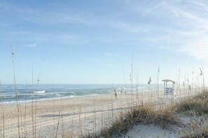 A beach with a sandy shore, a wooden structure with the number 23, and sparse vegetation. - Single Family Home On the Beach with Heated Pool! (Carolina Beach)