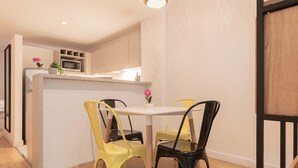 Cocina compacta con microondas, lavamanos y plantas en macetas. Hay dos sillas alrededor de una mesa pequeña.