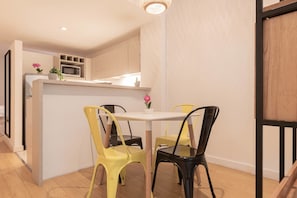 A compact kitchen with a microwave, sink, and potted plants. There are two chairs around a small table. - MOT Rentals + Paunero Loft in Alto Palermo (Buenos Aires)