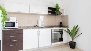 Eine moderne Küche mit weißen Schränken, einer Mikrowelle, einer Kaffeemaschine und einem Blumentopf.