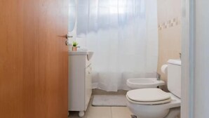 Ein kleines, kompaktes Badezimmer mit Toilette, Bidet und Waschbecken.