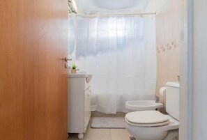 Ein kleines, kompaktes Badezimmer mit Toilette, Bidet und Waschbecken.