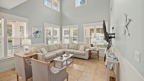 A spacious living room with a sectional sofa, a coffee table, and a TV mounted on the wall. - NEW to VRBO-FREE Golf & Activities ~Golf Cart~Hot tub, Pool, Gym (Miramar Beach)
