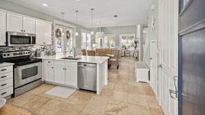 A modern kitchen with white cabinetry, stainless steel appliances, and a central island. - NEW to VRBO-FREE Golf & Activities ~Golf Cart~Hot tub, Pool, Gym (Miramar Beach)