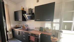Una cocina moderna con armarios negros, una encimera de madera y un horno empotrado.