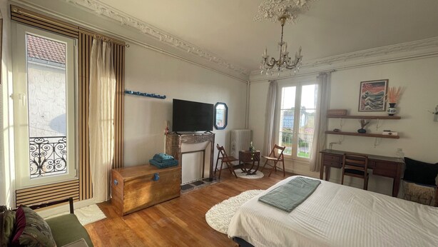 Un dormitorio con una cama, un escritorio, una silla, un televisor y una ventana con cortinas.