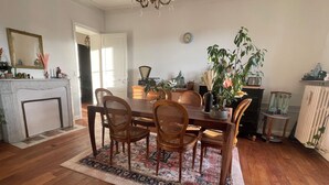 Un comedor con mesa de madera, sillas de mimbre, alfombra estampada y chimenea.
