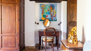 Una habitación con armarios de madera, un escritorio con silla y un cuadro abstracto y colorido en la pared.