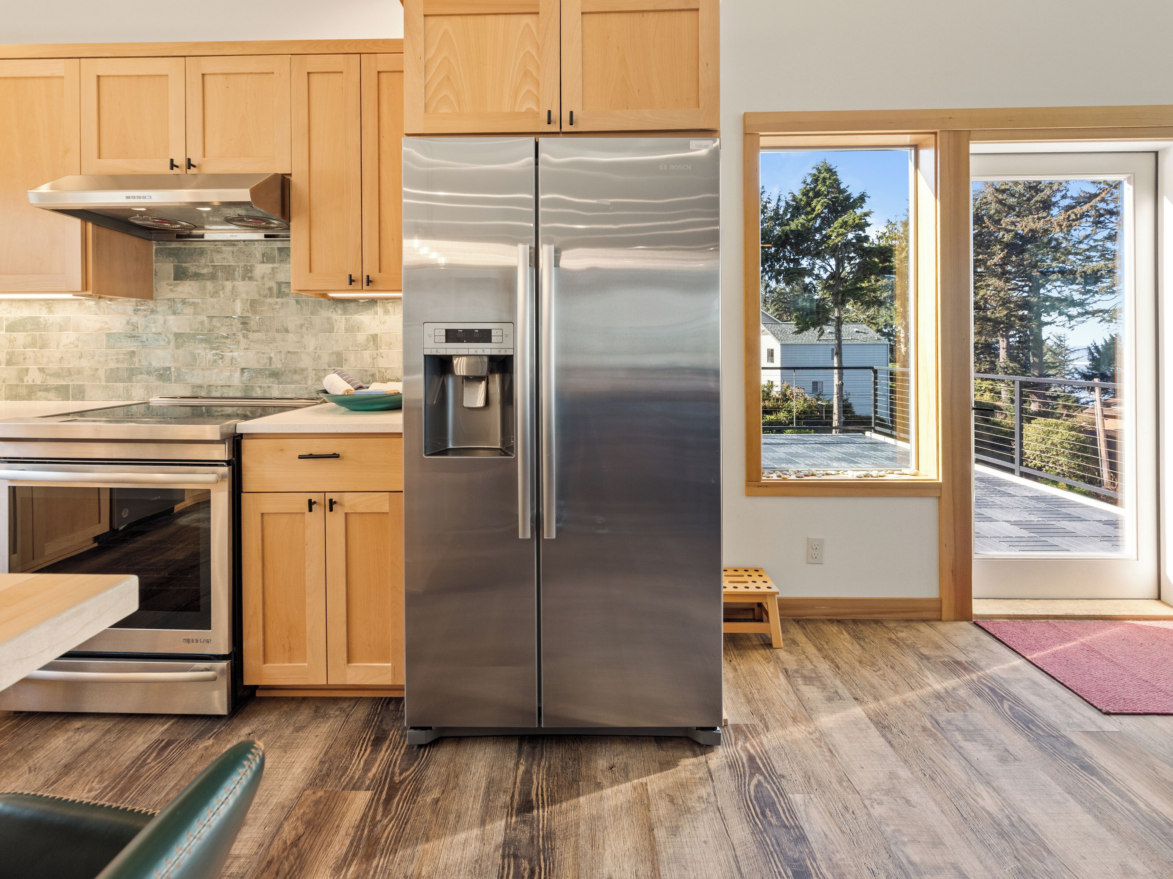 A modern kitchen with wooden cabinets, stainless steel appliances, and a built-in water dispenser.