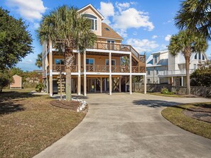 A two-story house with a balcony, a driveway, and a well-maintained lawn. - SunKissed Beach House | 2-Min Walk to Beach (Emerald Isle)