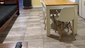 Habitació senzilla amb un llit, taula de fusta i cadires, pissarra i electrodomèstics de cuina.