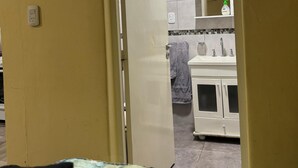 Una habitació amb un llit, una porta que dona a un bany, un lavabo i un mirall.