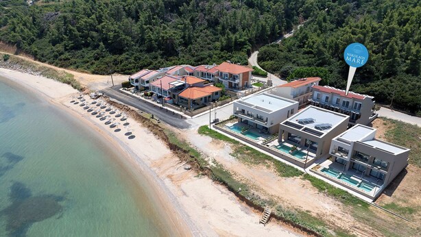 A coastal property with multiple modern buildings, a swimming pool, and a beach with sun loungers. - NikolaosMare  (Nea Propontida)