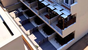 A multi-story residential building with balconies, outdoor seating, and a modern architectural design. - NikolaosMare  (Nea Propontida)