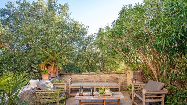 An outdoor patio with a wooden bench, two chairs, a table, and potted plants. - Villa Soleil d'Été – Heated Pool Near Beaches and Sainte-Maxime Center (Sainte-Maxime)
