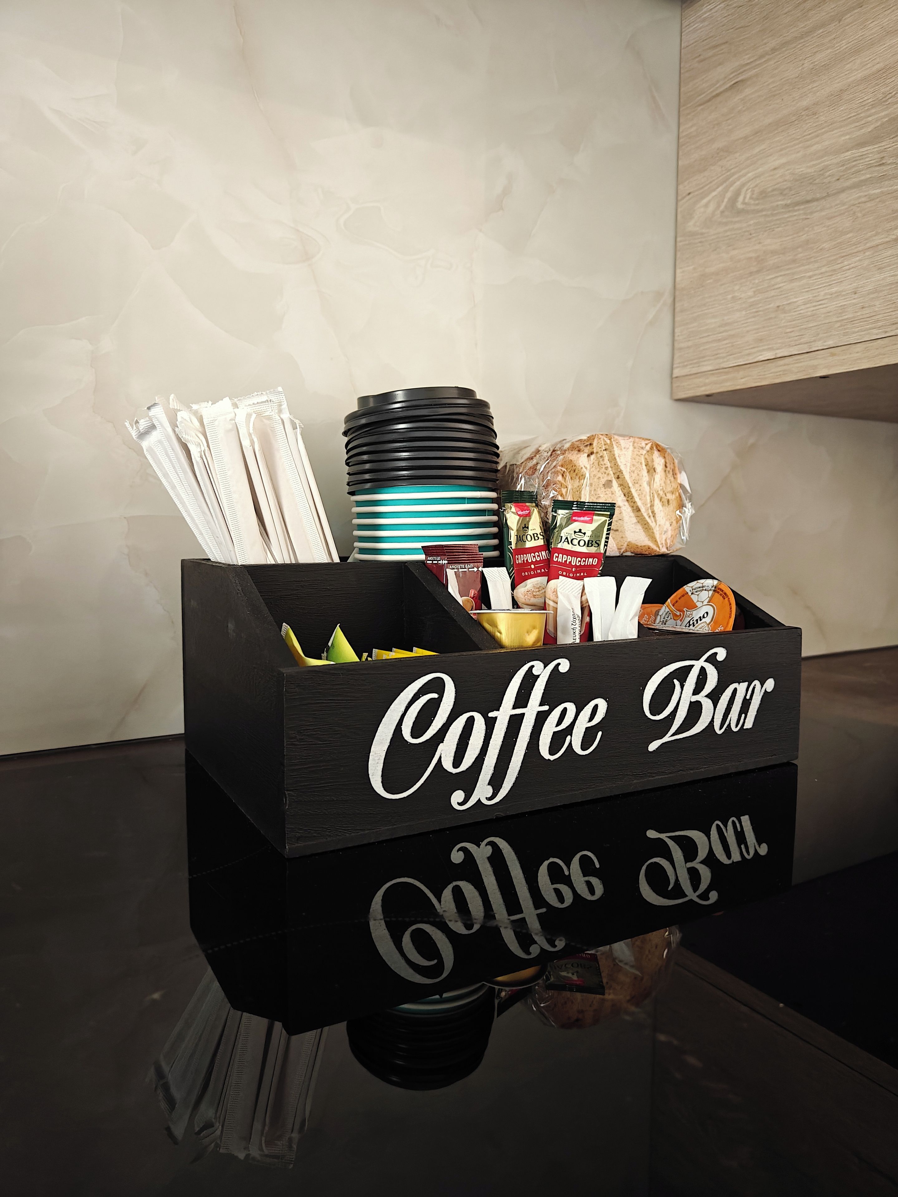 A coffee bar setup with a sign, cups, napkins, and snacks.