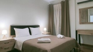 Ein ordentlich bezogenes Bett mit Kopfteil, zwei Nachttische mit Lampen, ein Holztisch und ein Spiegel an der Wand.