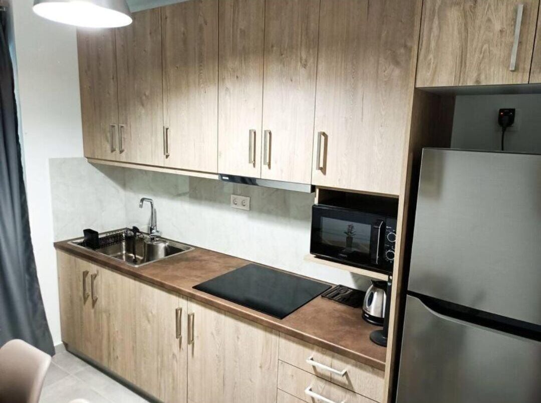 Una cucina compatta con mobili in legno, un frigorifero in acciaio inossidabile, un forno a microonde e un lavandino.