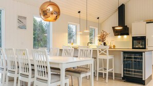 A modern kitchen with white cabinetry, a black range hood, and a built-in dishwasher. - 5 Star Holiday Home in Blokhus (Blokhus)