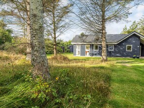 Une maison à l’extérieur sombre, avec une porte bien visible et une petite dépendance attenante.