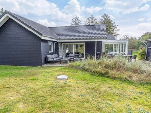 A modern house with a covered patio, a lawn, and a small garden area. - 5 Star Holiday Home in Blokhus (Blokhus)