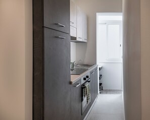 A modern kitchen with dark cabinets, a stainless steel sink, and a window with a view. - Elegant apartment in the heart of Palermo - Ideal for families (Palermo)