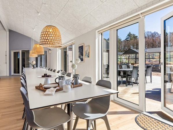 Un espace de restauration moderne avec une longue table, des chaises et une grande fenêtre donnant sur l’extérieur.