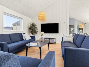 Ein modernes Wohnzimmer mit zwei Sofas, einem Couchtisch, einem Fernseher und einem großen Fenster.