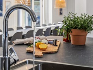 Un plan de travail de cuisine avec une planche à découper, un pot contenant une plante aromatique et une râpe.