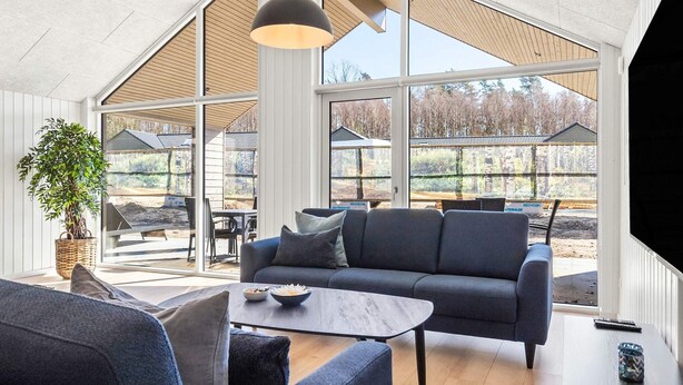En modern inredning med ett stort fönster, en soffa, ett bord och en krukväxt.
