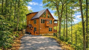 Une cabane en bois dotée d’un balcon, entourée d’arbres.