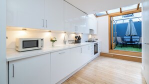 Uma cozinha moderna com armários brancos, micro-ondas e uma área de refeições com mesa e cadeiras.