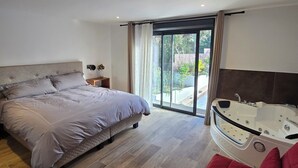 Une chambre moderne avec un grand lit, un canapé rouge et un bain à remous.