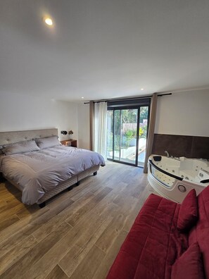 Ein modernes Schlafzimmer mit einem großen Bett, einem roten Sofa und einer Whirlwanne.