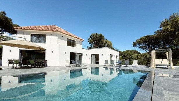 Une maison moderne dotée d’une piscine, d’un espace salon extérieur et d’une pergola.