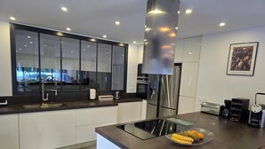 Une cuisine moderne dotée d’un îlot central, d’appareils électroménagers en acier inoxydable et d’une grande fenêtre.