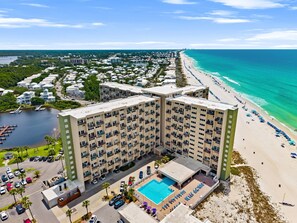 A high-rise hotel with a pool, beachfront view, and multiple balconies. - New To Rentals | Fully Renovated Pinnacle Port 319A | Gulf & Lake Views (Panama City Beach)