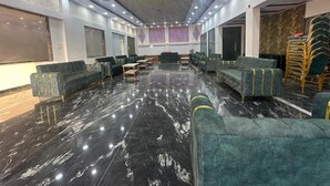 A spacious lobby with a marble floor, green upholstered sofas, and a patterned ceiling. - Amantran Palace (Mohania)