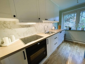 A modern kitchen with marble countertops, a built-in oven, and a window with plants. - 4 Star Holiday Home in Alingsas (Alingsas)