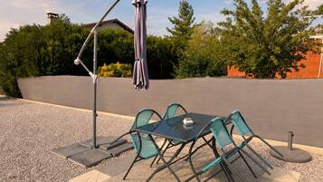 An outdoor patio with a table and chairs, a patio umbrella, and a pergola.