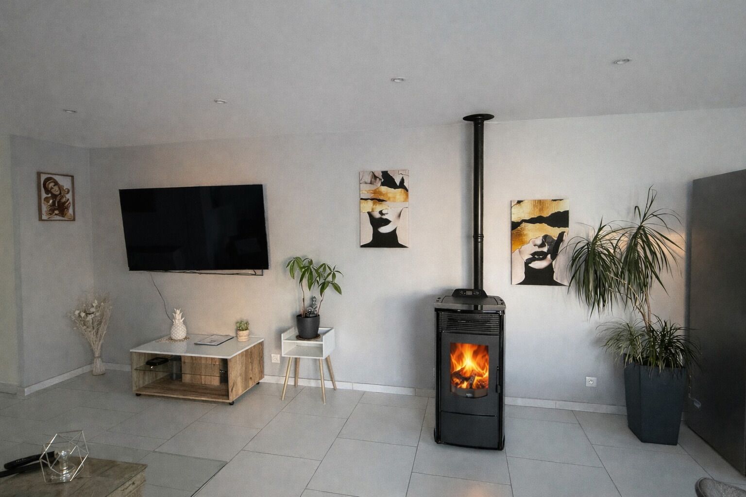 A living room with a TV, a fireplace, and artwork on the walls.