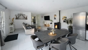 Una sala de estar moderna con un sofá, una mesa de comedor, sillas y una chimenea.