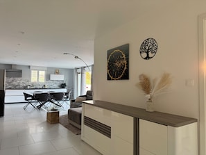 Une cuisine moderne avec un coin repas, un salon doté d’un canapé et un mur agrémenté de deux éléments décoratifs.