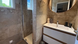 Un bagno moderno con doccia vetrata, specchio rotondo e mobile lavabo bianco.