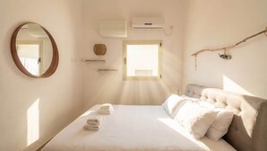 Una camera da letto con un letto, uno specchio, un condizionatore d'aria, una finestra e una mensola a parete.